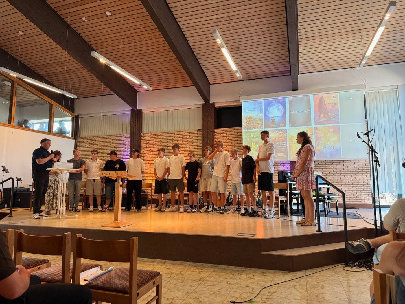 Jugendliche stehen im Gottesdienst gemeinsam vorne im Gemeindesaal in Bechterdissen